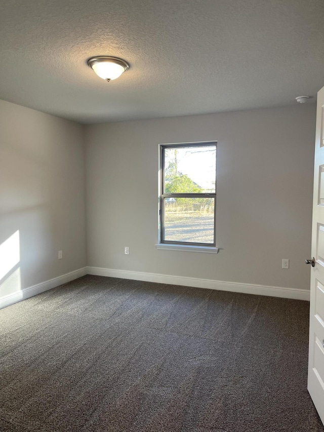 empty room featuring dark carpet and a textured ceiling