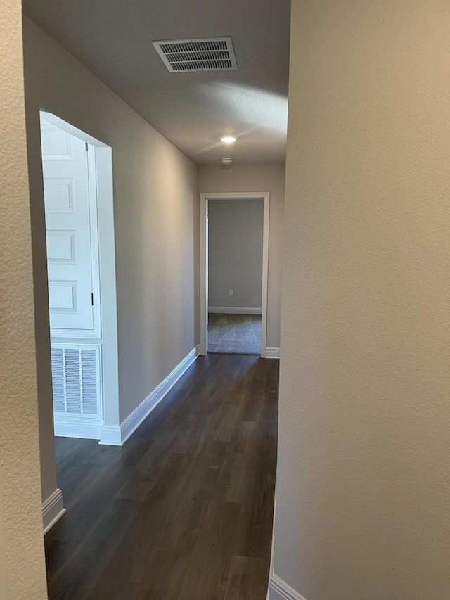 corridor with dark hardwood / wood-style floors and a textured ceiling