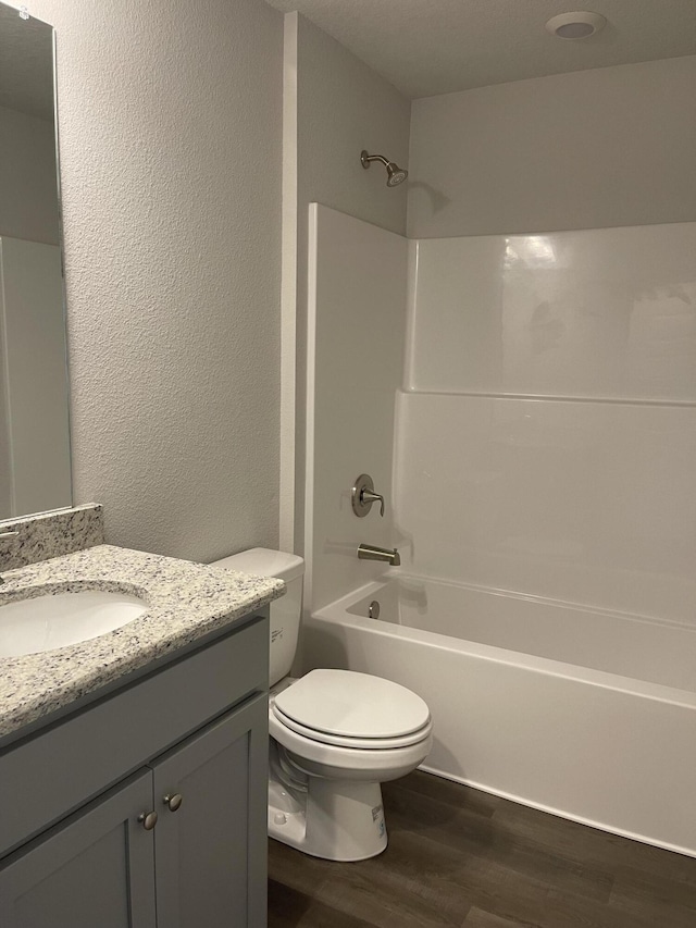 full bathroom featuring hardwood / wood-style flooring, vanity, shower / bathtub combination, and toilet