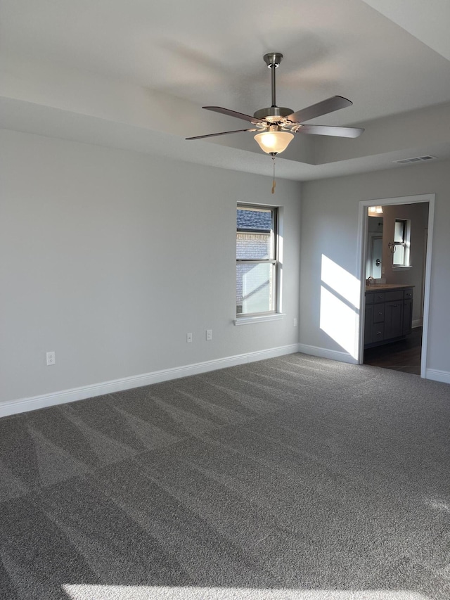 spare room featuring dark colored carpet and ceiling fan