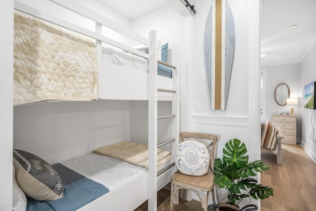 bedroom with a barn door, ornamental molding, and hardwood / wood-style flooring