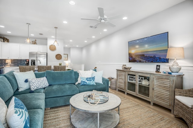 living area featuring recessed lighting, light wood-type flooring, a ceiling fan, and wainscoting