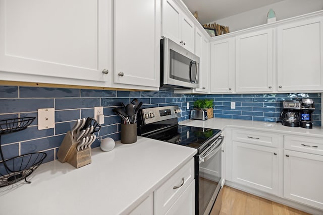 kitchen with backsplash, light countertops, appliances with stainless steel finishes, light wood-style floors, and white cabinets