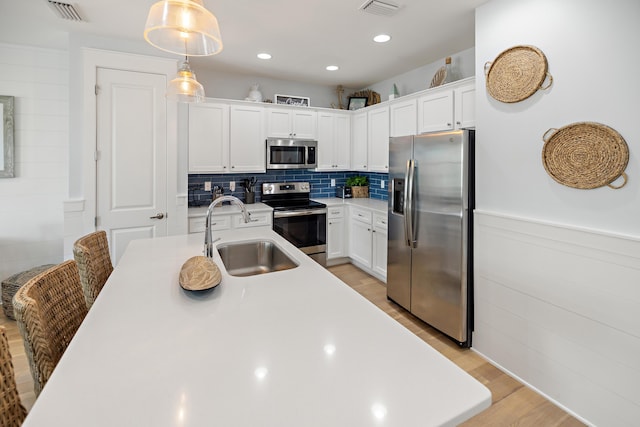 kitchen with a sink, stainless steel appliances, light wood-style floors, and visible vents