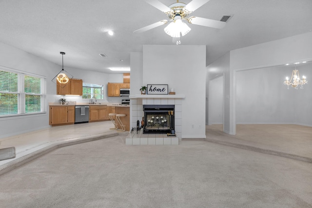 carpeted living room with ceiling fan with notable chandelier, sink, a tile fireplace, and a textured ceiling