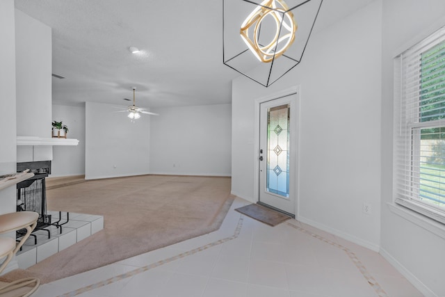 entrance foyer featuring a tiled fireplace, light tile patterned flooring, and ceiling fan