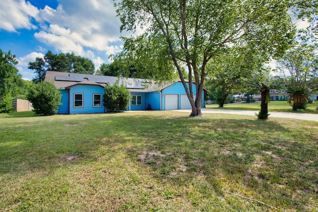 view of front of home featuring a garage, a front yard, and solar panels