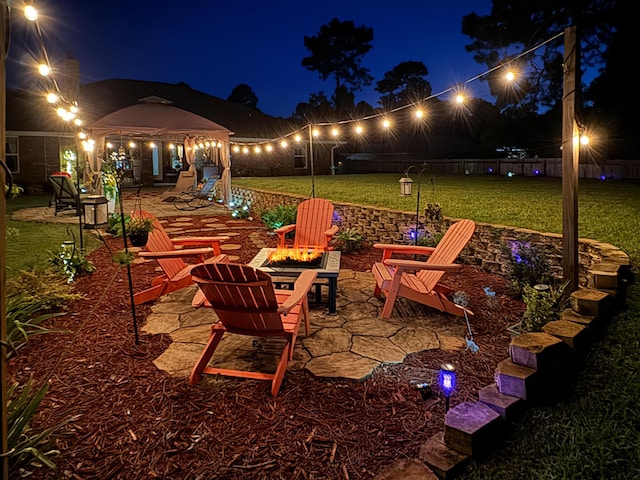 patio at twilight featuring a yard and a fire pit