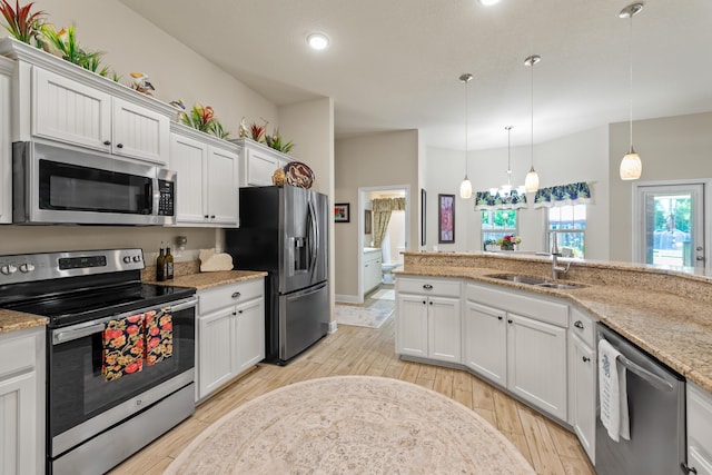 kitchen with sink, light stone counters, decorative light fixtures, white cabinets, and appliances with stainless steel finishes