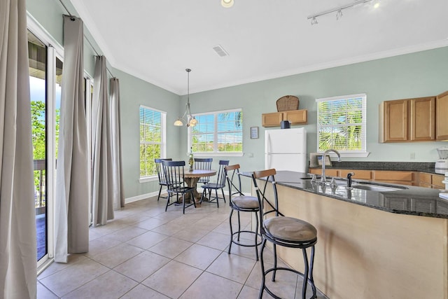 kitchen featuring a breakfast bar, an inviting chandelier, white refrigerator, sink, and hanging light fixtures