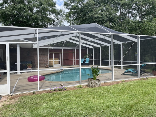 view of pool featuring a patio, a yard, and glass enclosure