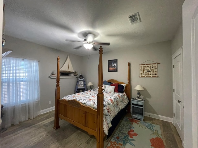 bedroom with ceiling fan, wood-type flooring, and a textured ceiling