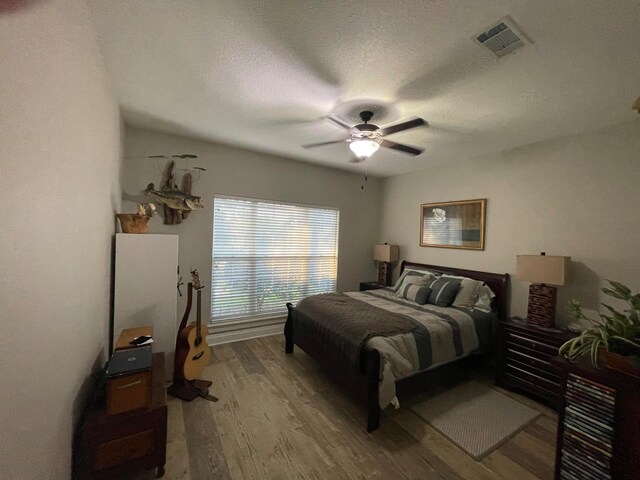 bedroom with hardwood / wood-style floors, a textured ceiling, and ceiling fan