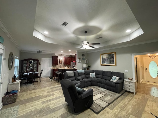 living room with crown molding, a tray ceiling, and light hardwood / wood-style flooring