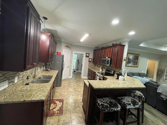 kitchen featuring pendant lighting, sink, appliances with stainless steel finishes, ornamental molding, and kitchen peninsula