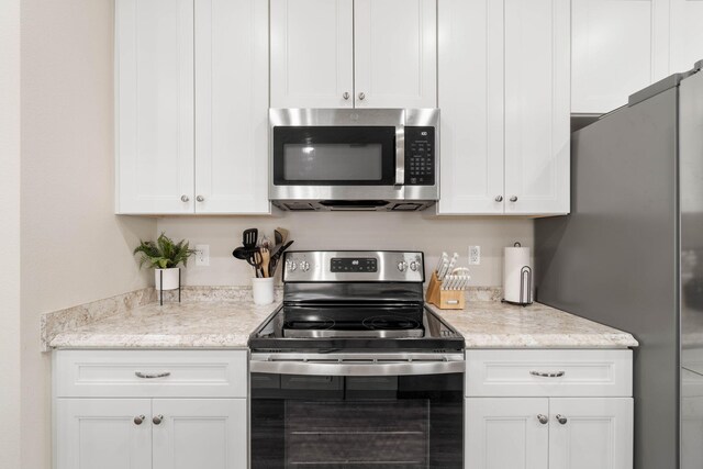 kitchen featuring appliances with stainless steel finishes, white cabinets, and light stone countertops