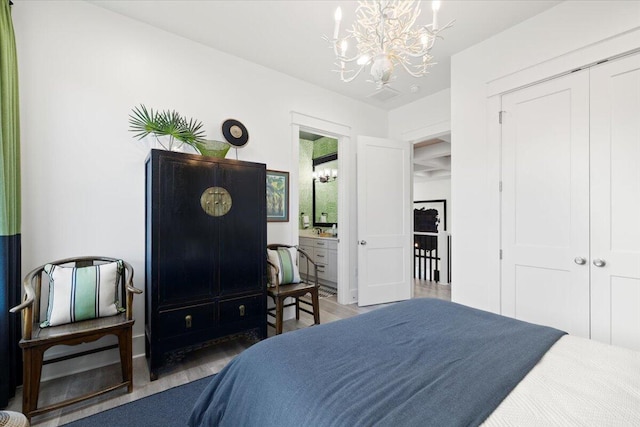 bedroom featuring ensuite bathroom, an inviting chandelier, a closet, and dark hardwood / wood-style floors