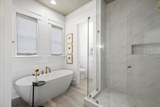 bathroom with toilet, wood-type flooring, and shower with separate bathtub