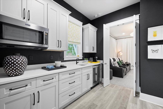 kitchen featuring white cabinetry, sink, light hardwood / wood-style floors, and appliances with stainless steel finishes