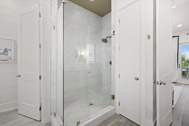 bathroom with a tile shower and wood-type flooring