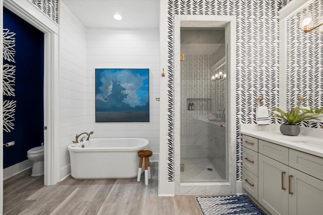 full bathroom featuring toilet, wood-type flooring, vanity, and separate shower and tub