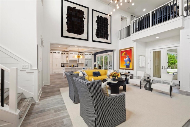 living room featuring plenty of natural light, french doors, a high ceiling, and light wood-type flooring