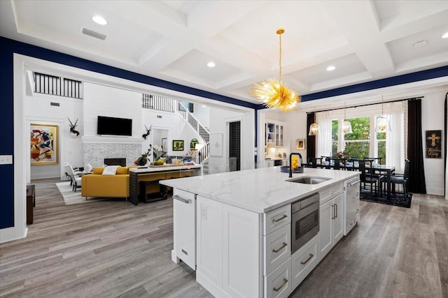 kitchen with pendant lighting, white cabinets, sink, light stone countertops, and stainless steel appliances