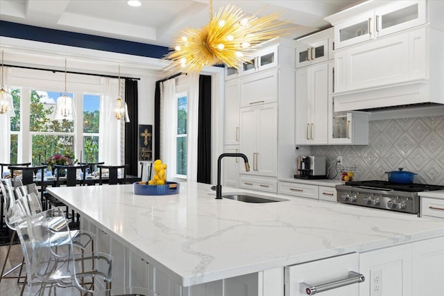 kitchen featuring tasteful backsplash, sink, white cabinets, and decorative light fixtures