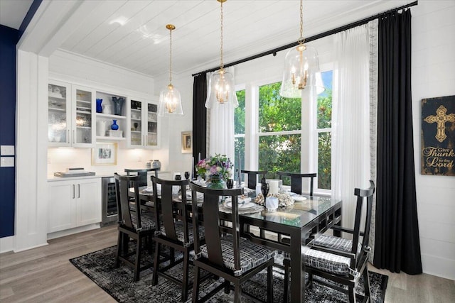 dining room featuring wood-type flooring, crown molding, wine cooler, and an inviting chandelier