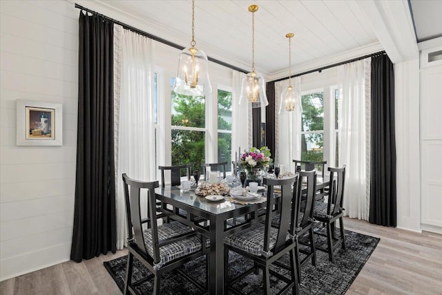 dining space with light wood-type flooring, crown molding, and a notable chandelier