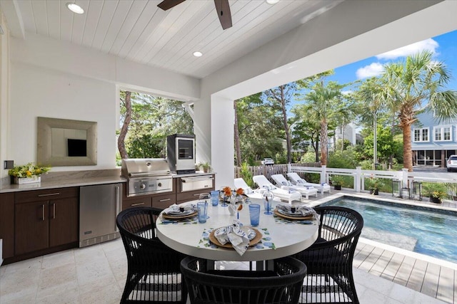 view of patio with ceiling fan, a grill, a fenced in pool, and exterior kitchen