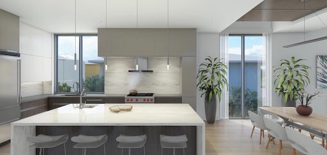 kitchen with gray cabinetry, backsplash, light hardwood / wood-style flooring, and a center island with sink