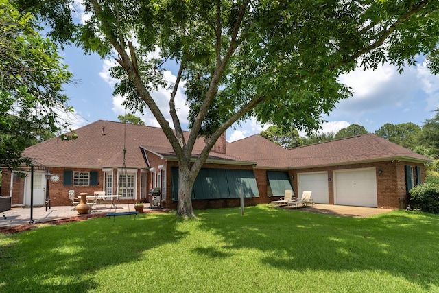 back of house featuring a garage, a patio, and a lawn