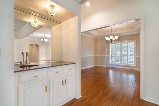 interior space with sink, hardwood / wood-style flooring, white cabinetry, hanging light fixtures, and a chandelier