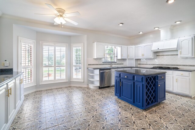 kitchen with blue cabinetry, appliances with stainless steel finishes, a center island, ornamental molding, and white cabinets