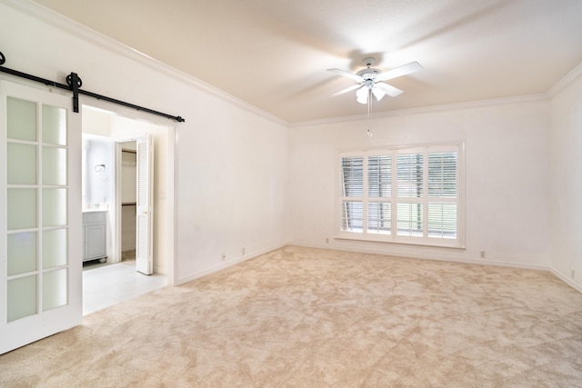 unfurnished room with crown molding, light colored carpet, a barn door, and ceiling fan