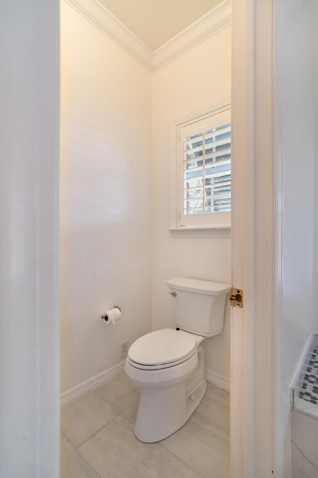 bathroom featuring tile patterned flooring, ornamental molding, and toilet