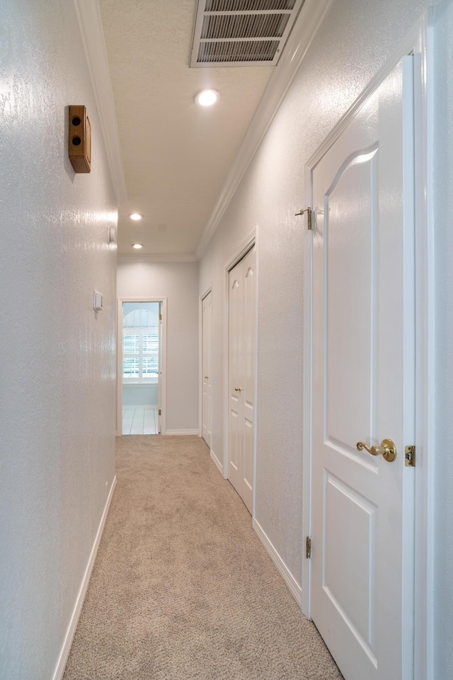 hall with light colored carpet and ornamental molding