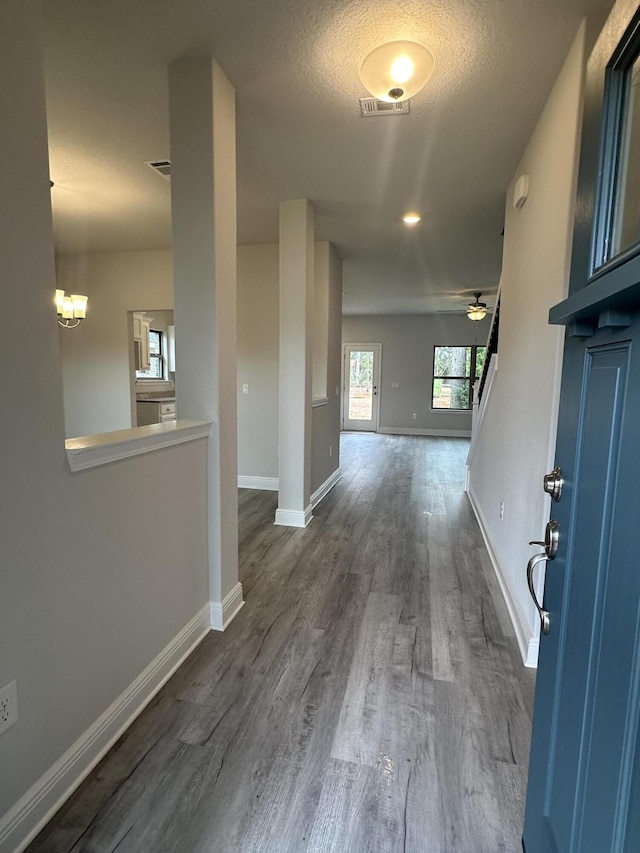 hall featuring a textured ceiling, dark wood-type flooring, and a notable chandelier