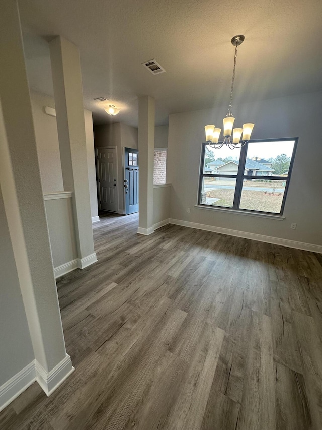 unfurnished dining area featuring hardwood / wood-style flooring and an inviting chandelier