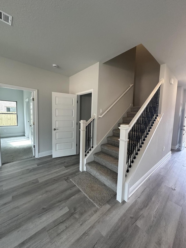 stairs with wood-type flooring and a textured ceiling