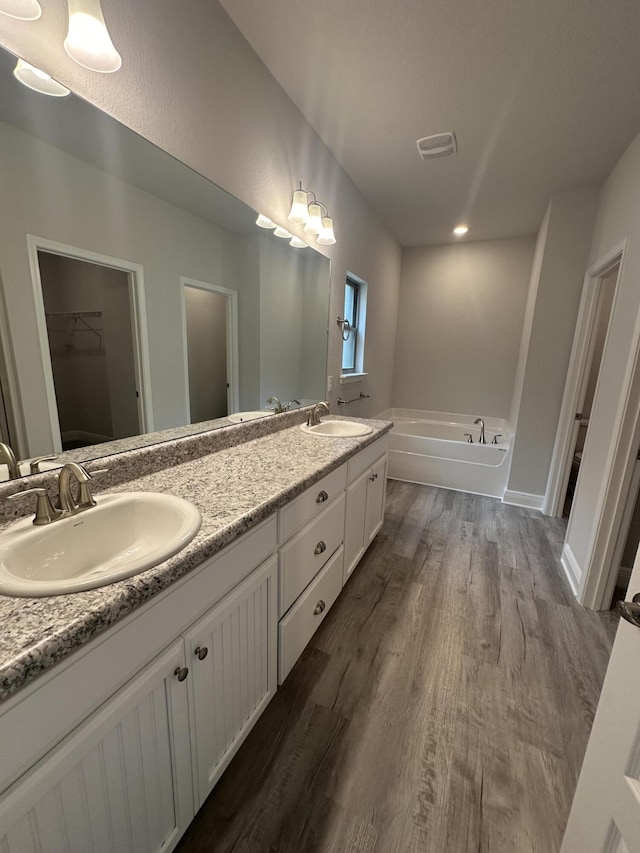 bathroom featuring hardwood / wood-style floors, vanity, and a bath