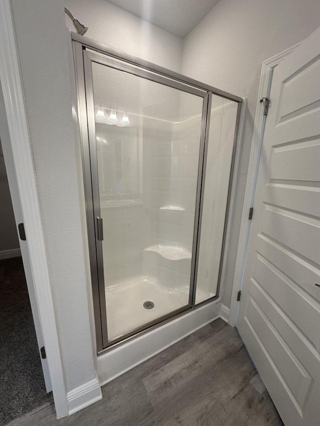 bathroom with a shower with shower door and wood-type flooring