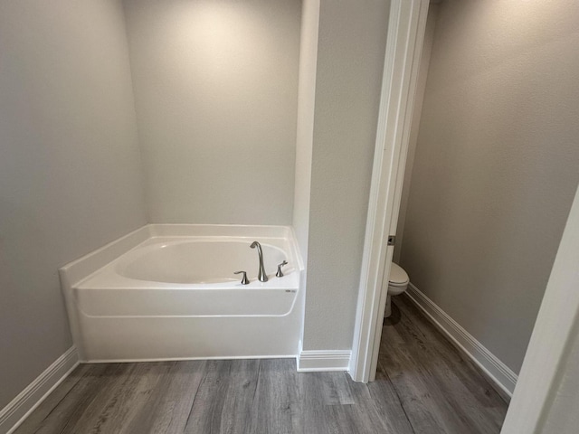 bathroom featuring hardwood / wood-style floors, a bathtub, and toilet