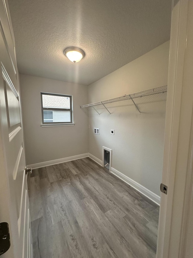 laundry room featuring electric dryer hookup, washer hookup, a textured ceiling, and hardwood / wood-style flooring