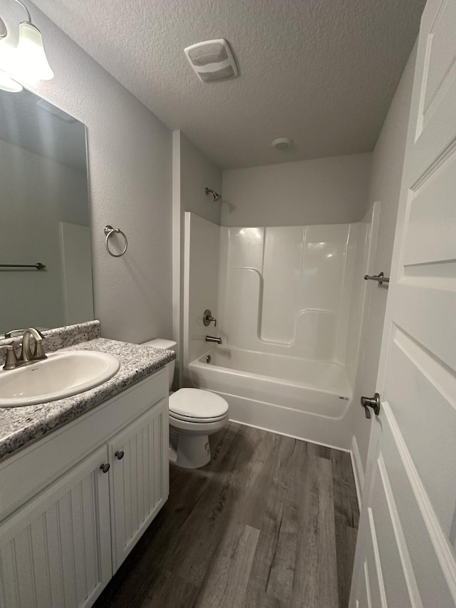 full bathroom with vanity, a textured ceiling, shower / tub combination, hardwood / wood-style flooring, and toilet