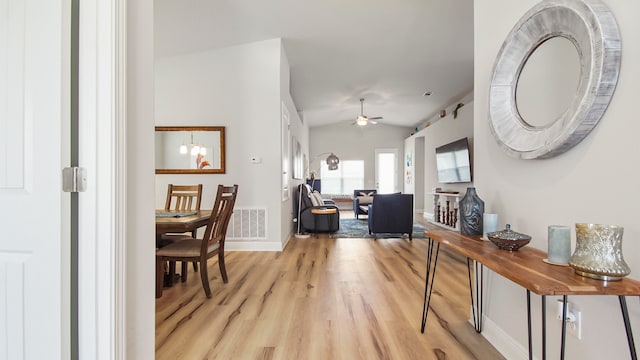 interior space featuring vaulted ceiling, ceiling fan with notable chandelier, and light hardwood / wood-style floors