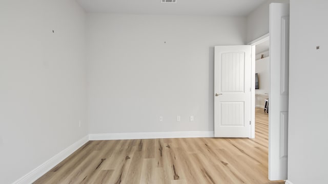 unfurnished room with visible vents, light wood-style flooring, and baseboards