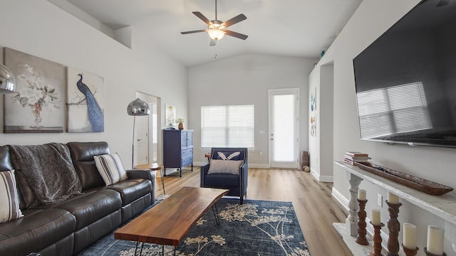 living area featuring light wood finished floors, ceiling fan, baseboards, and vaulted ceiling