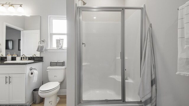 bathroom with vanity, toilet, hardwood / wood-style floors, and an enclosed shower